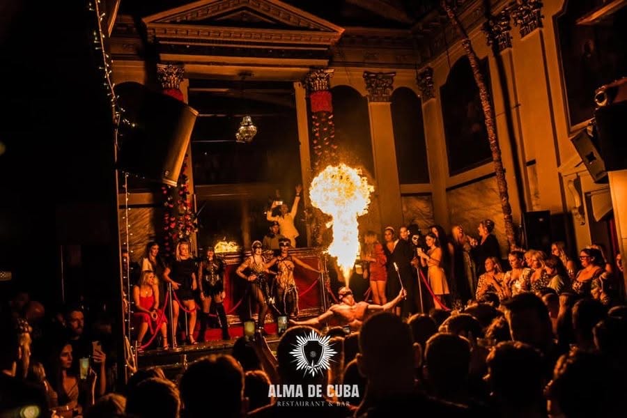 A fire-breathing performer entertains a packed crowd during a live event at Alma de Cuba, Liverpool.